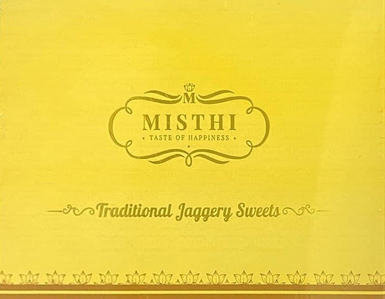 The gold Misthi gift box lid, printed with the Misthi lockup, Traditional Jaggery Sweets and a lotus border